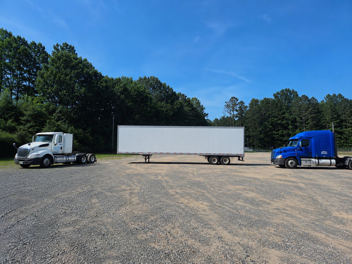 The training lot today — the school's day-cab truck, 53-foot trailer, and blue Freightliner parked on the secured gravel lot in Dalton