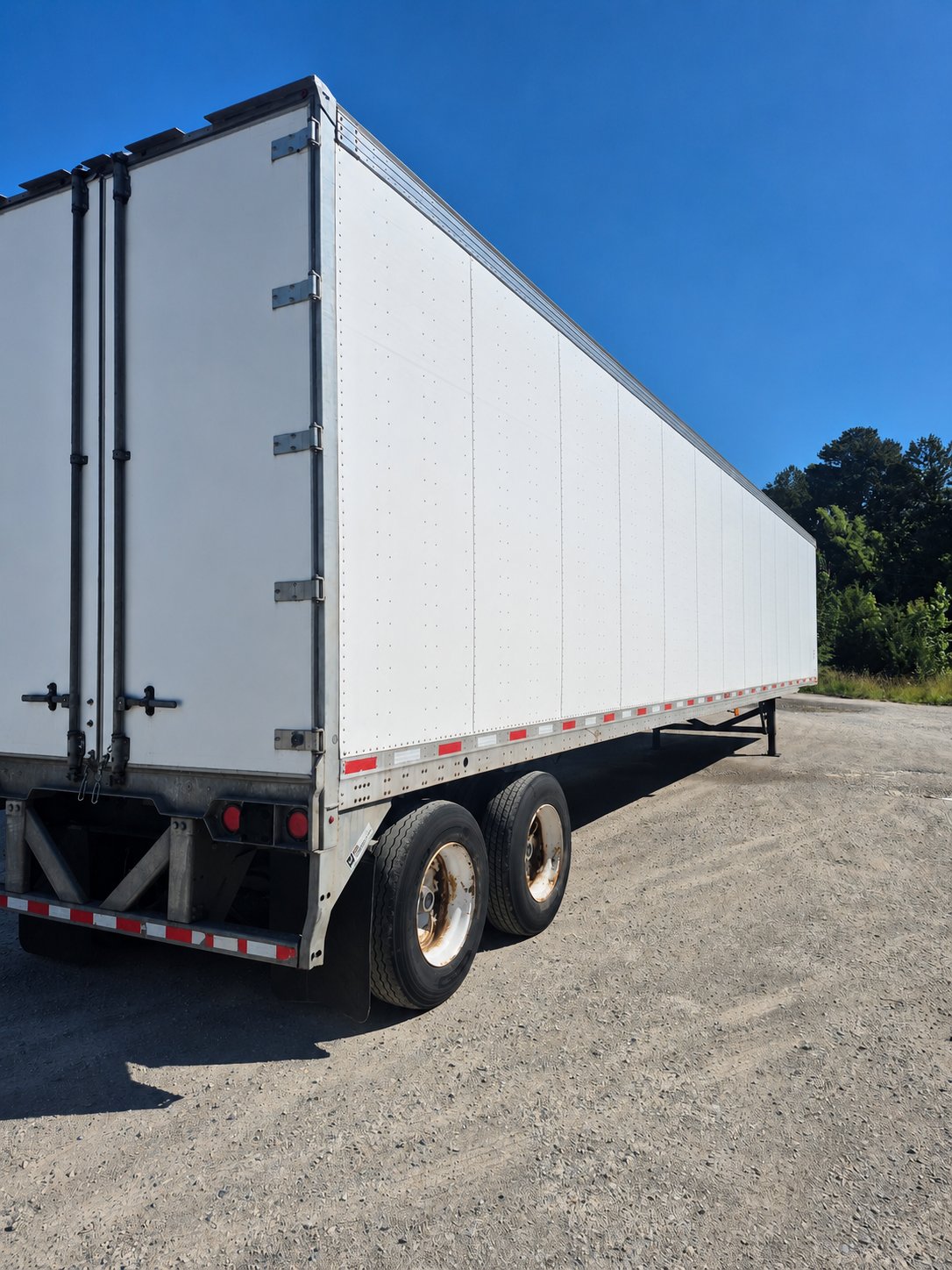 The school's 53-foot dry van trailer with a wide blank white side ready for a sponsor logo